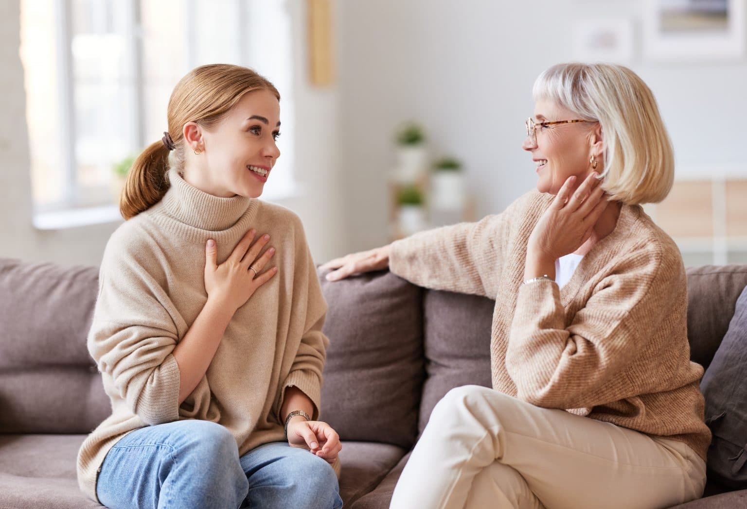 Mother and daughter sitting on sofa at home discussing hoarseness