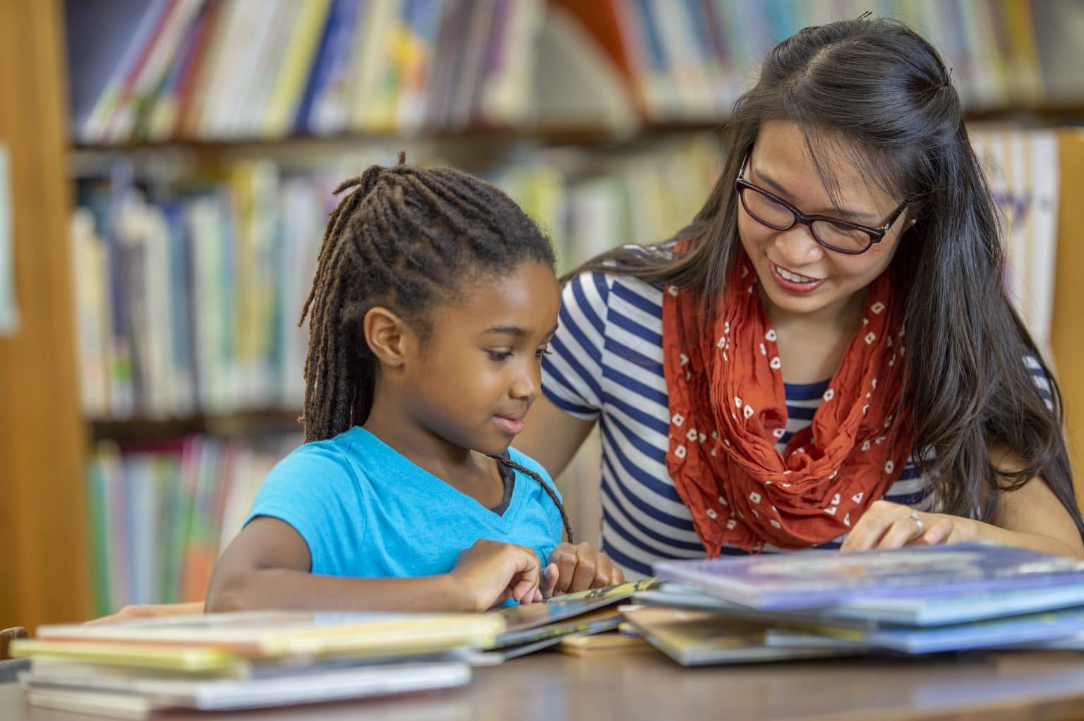 A female teacher is helping a child female student with a speech and language therapy.