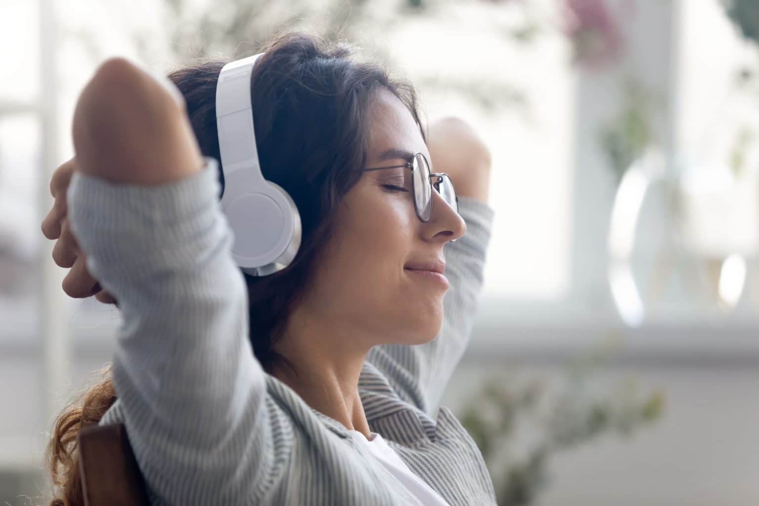 Woman sitting with headphones on experiencing clear nasal passages after clarifix treatment