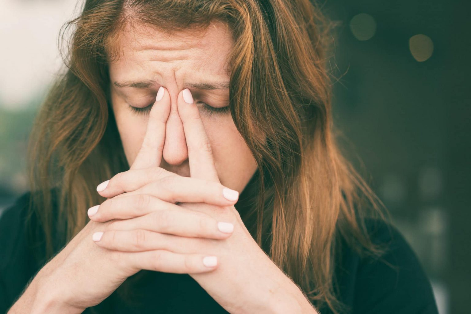 Woman puts her index fingers on her nose from nasal pressure before seeking inferior turbinate reduction treatment.